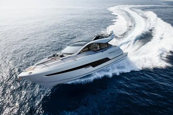 A luxury yacht speeds across blue water, leaving a wake behind, showcasing sleek design and modern features.